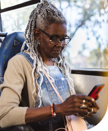 A woman is sitting on a bus looking at her phone